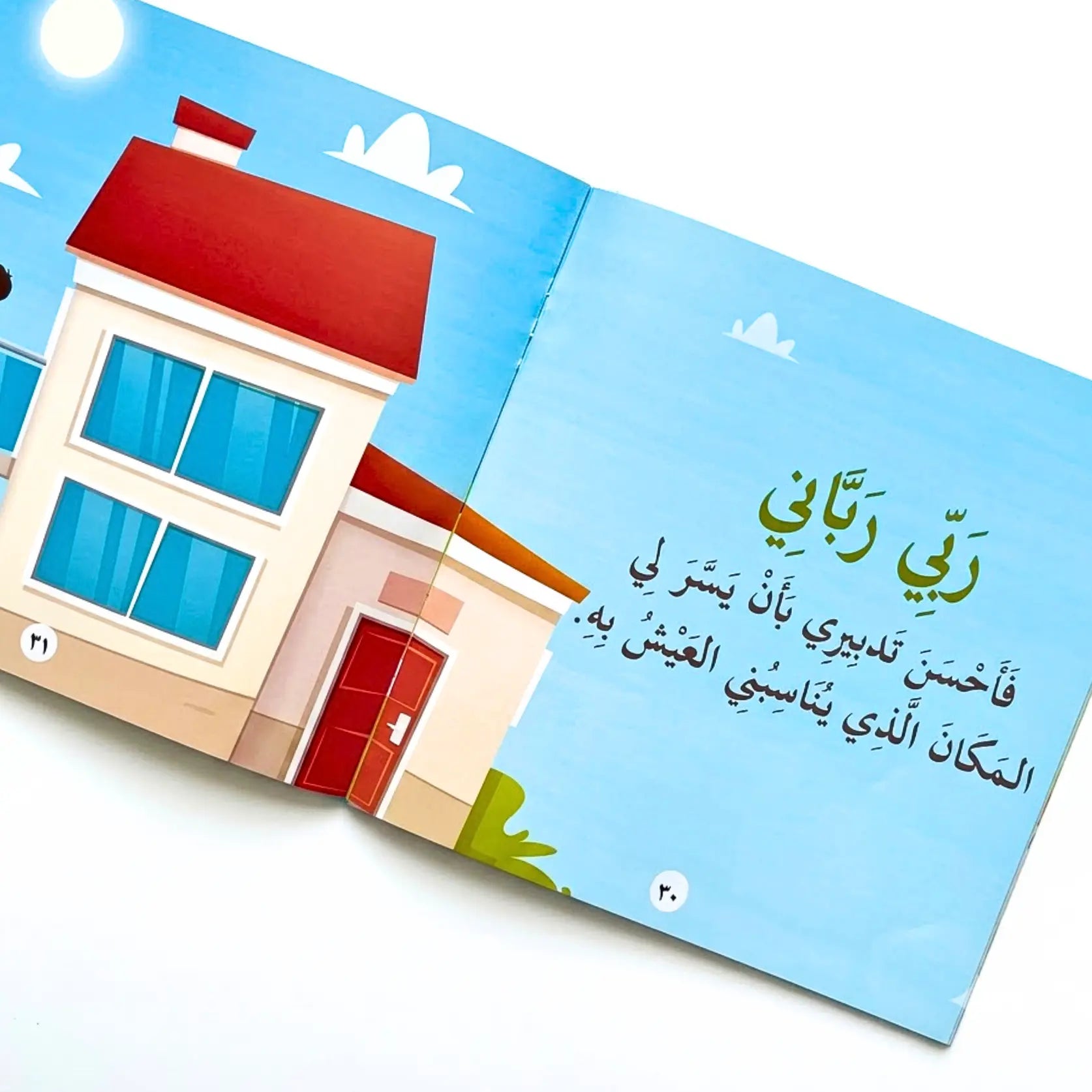 Children's book with a house illustration and Arabic text on a blue sky background