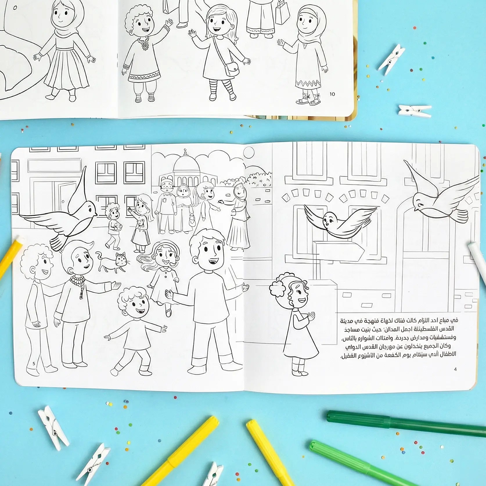 Coloring book open to a page with children and birds on a blue background with coloring supplies.