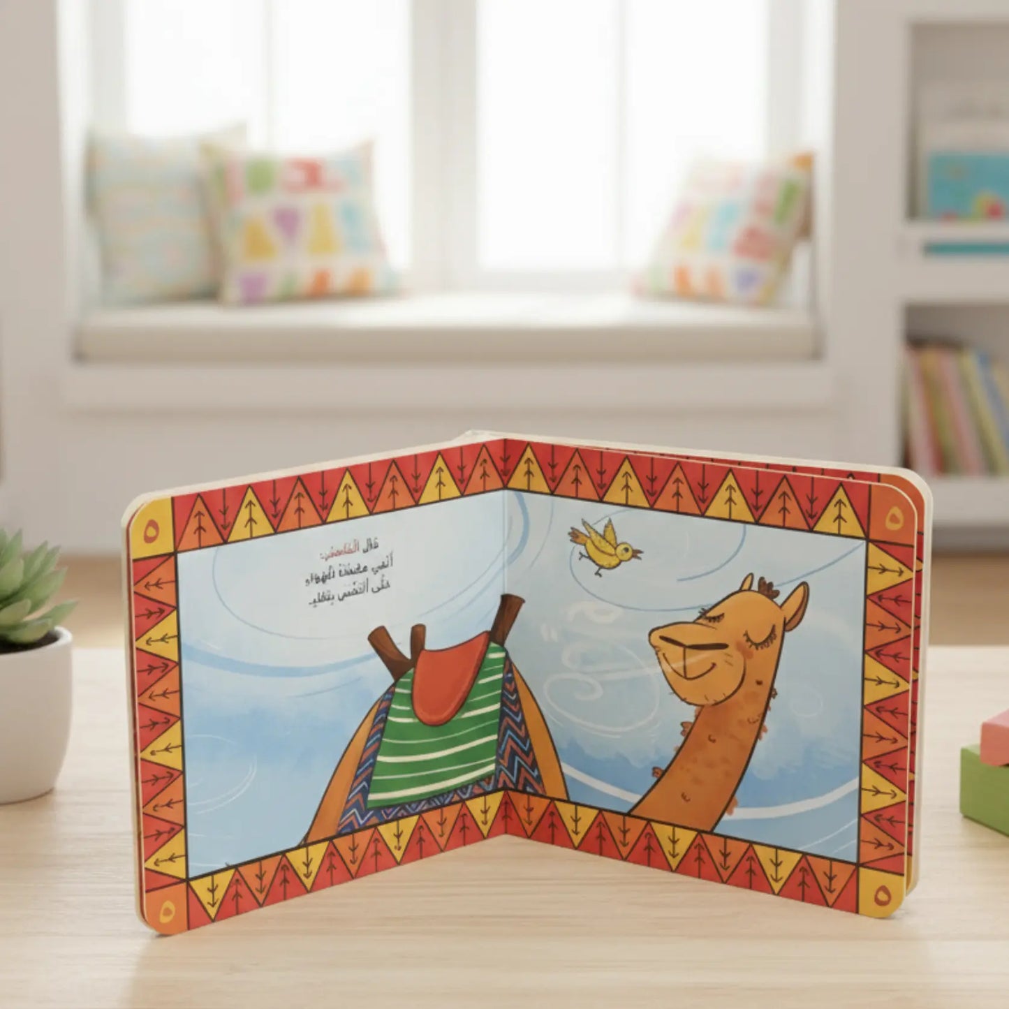 Children's book open to a page with a camel and bird illustration on a wooden surface.