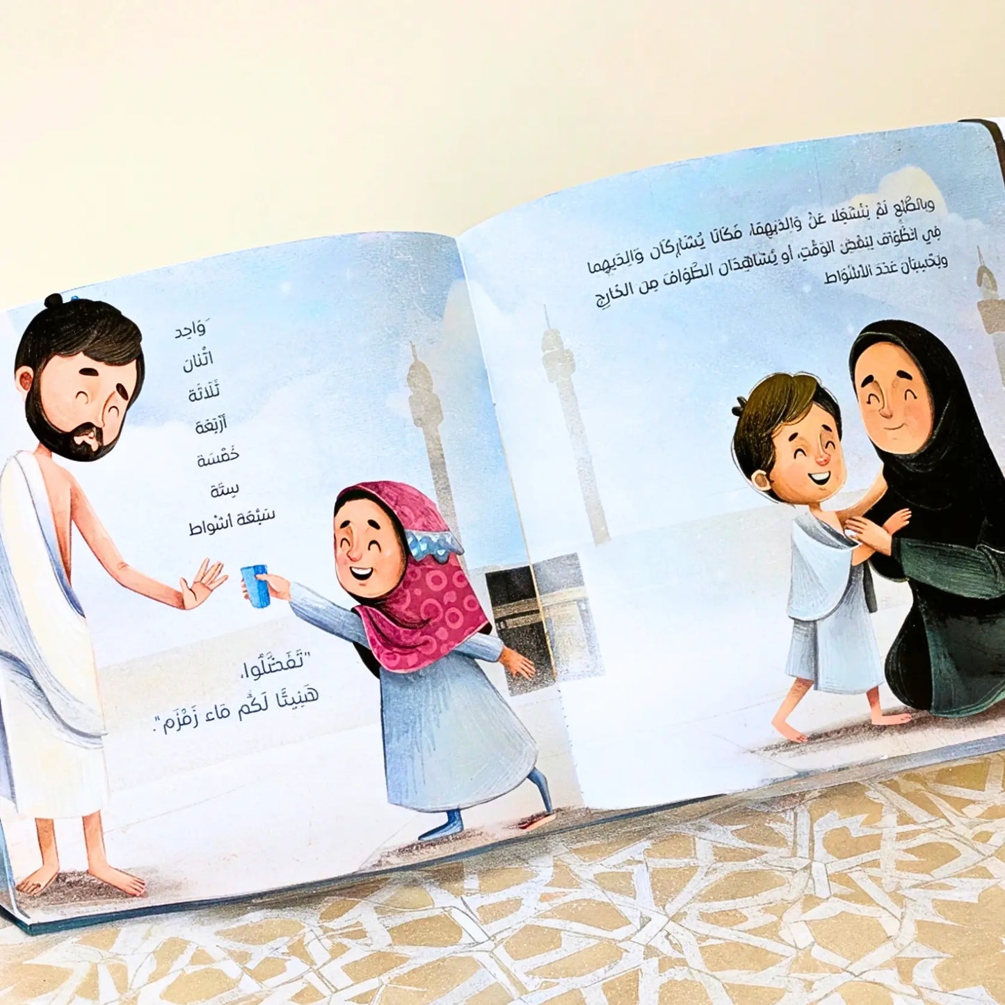 Open book with illustrated pages showing a family and a mosque on a white background